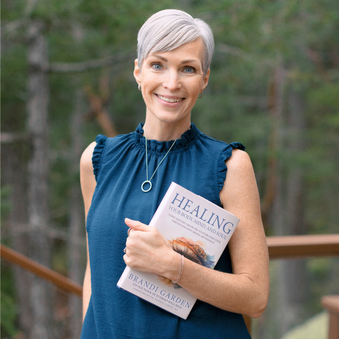 Woman holding a book titled 'Healing' by Brandi Garden outdoors.